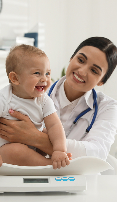 Pediatra pesa un neonato sulla bilancia dell'ambulatorio
